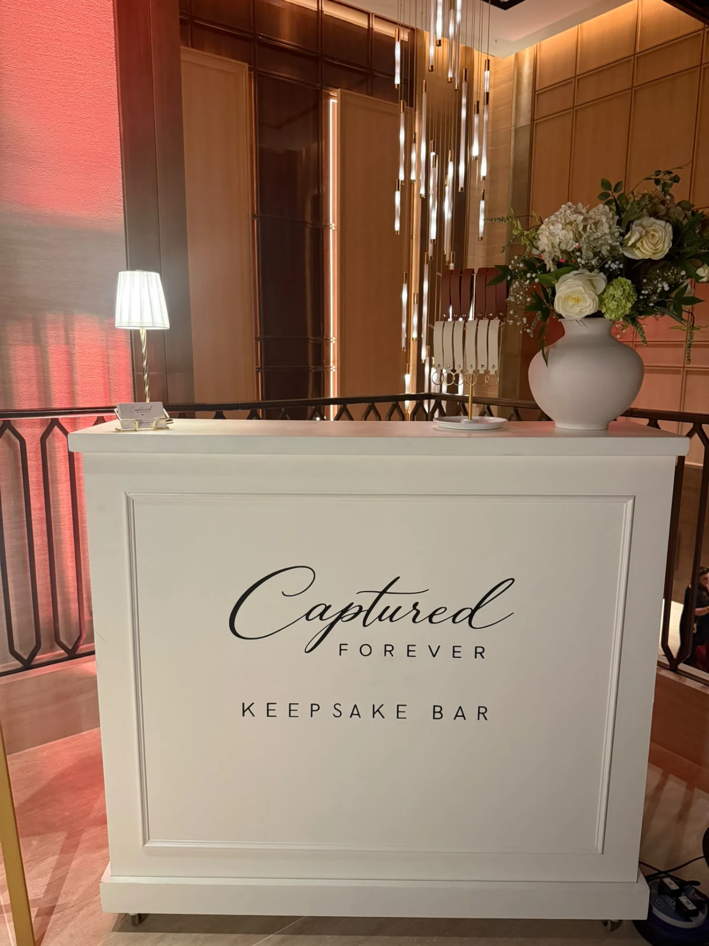 The white Captured Forever Keepsake Bar styled with flowers at a luxury hotel venue